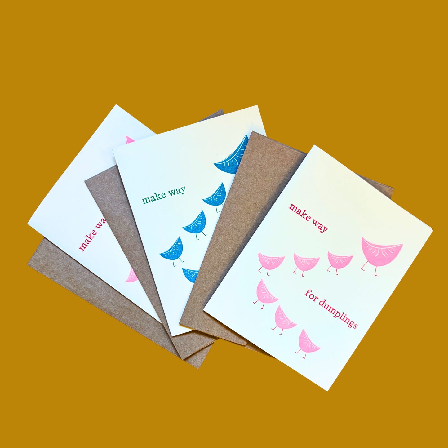 Set of three greeting cards with dumpling-themed illustrations on a tan background