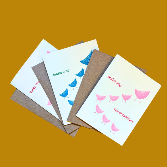 Set of three greeting cards with dumpling-themed illustrations on a tan background
