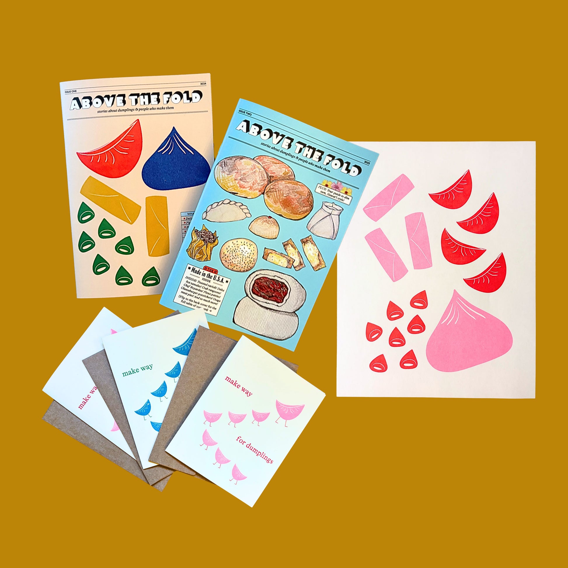 Issue 1 and Issue 2 of the Above the Fold zine with three notecards and the pink and red dumpling print